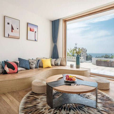 Bright living room with ocean view, round coffee table, cozy seating area, and modern decor accents.