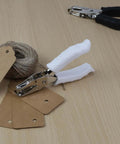One Quarter Inch Circle Hole Puncher with soft grip handle on a table with tags and twine, ideal for crafting projects.