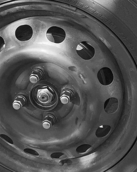 Close-up of a wheel with a pair of M26x15 Front CV Shaft Axle Nuts made from heat treated steel for Honda Accord and Acura.