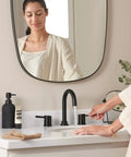 Woman using Precept Widespread Matte Black Bathroom Faucet For 3-Hole 6-16 In. Install With ADA Push Pop-Up Drain