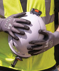 Cut Resistant Work Gloves With Nitrile Coated Grip, HPPE Fabric For Flexibility And Dexterity, Touchscreen Compatible, ANSI A4, XL Size, 2 Pack For Pro Level Handling And All Day Comfort being worn while holding a hard hat.