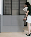 Woman securing Retractable Baby Gate With One Way Lock Mesh Extends From 55 To 71 Inches Wide And 33 Inches Tall Safety Gate