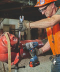 Person using Heavy Duty 18 Volt Cordless Impact Wrench With Half Inch Drive Friction Ring And Beast Mode Torque on a large red pipe.