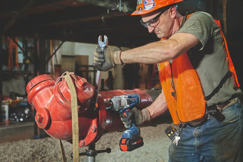 Person using Heavy Duty 18 Volt Cordless Impact Wrench With Half Inch Drive Friction Ring And Beast Mode Torque on a large red pipe.