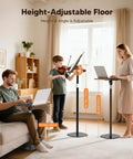 All In One Floor And Desktop Wooden Book And Music Stand That Do It All With Solid Wood Build Adjustable Height From Sixteen Point Five To Fifty One Inches Hands Free Reading Stand With Page Clip For Cookbooks Sheet Music Bible Office And Home shown being used in a living room by people for reading and playing music.