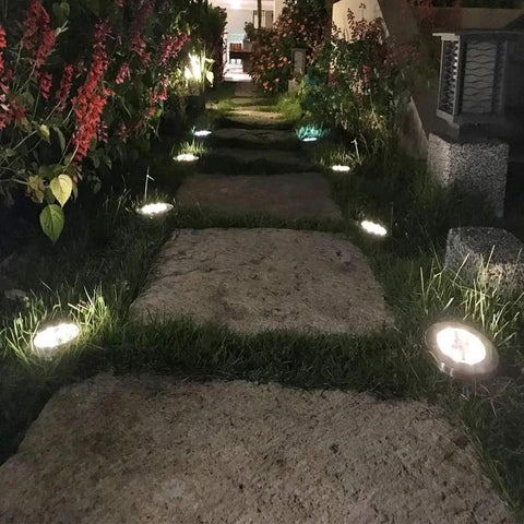 Night view of garden path illuminated by 16 Pack Solar Ground Lights Waterproof Outdoor Landscape Pathway Lights With Upgraded Aluminum Build Built To Last In Ground Yard Deck Lawn Patio Lighting Bright White LED Walkway Lights.