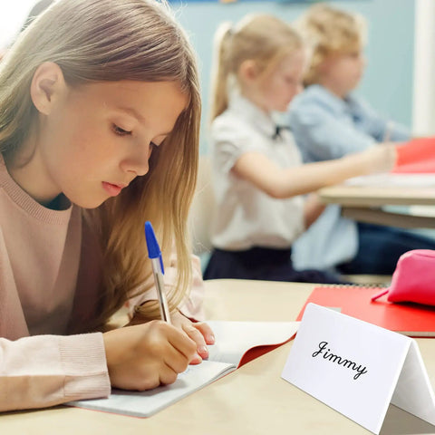 Girl in classroom using 20 Pack Dry Erase Name Tent Cards with Black Markers No Fuss Wipe Clean Reusable Desk Tags 8.7 x 2.8 x 1.9 inches.