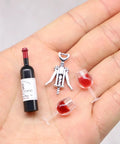 Hella Cool Miniature Red Wine Bottle Set featuring two resin filled wine glasses and a corkscrew on a hand.