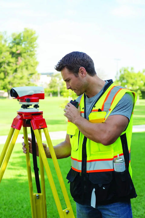 Mens Premium Surveyor Vest Class 2 Hi Vis Safety Vest Ten Roomy Pockets Heavy Duty Zip Rock Solid High Visibility Workwear Built Tough For The Daily Grind Large Lime And Black on a worker using surveying equipment.
