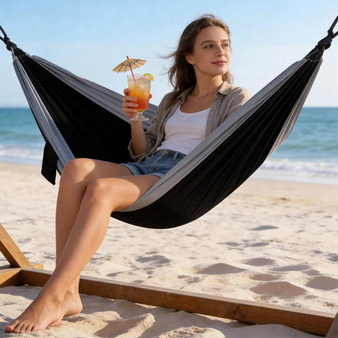 Woman relaxing on a beach in a Portable Double Camping Hammock With Tree Straps And Carry Bag 600Lb Nylon Outdoor Lounge For Travel Hiking Beach Backyard Or Indoor Use Ultra Comfy Parachute Nylon Construction Quick Drying For All Season Comfort.