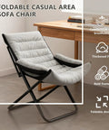 Gray folding casual area sofa chair with thick fill and bold frame, displayed near a wooden desk.
