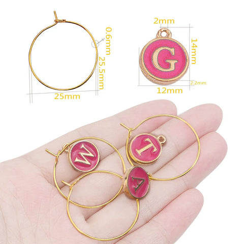 Hand holding Rose Red Enamel Alphabet Charms And Golden Wine Glass Marker Rings Set Including 52 Alphabet Charms And 60 Marker Rings For Wine Tasting Parties Party Favors Gift Decor And Beading Hoops For Diy Jewelry Or Crafts, showing letters M, T, and A with size chart.