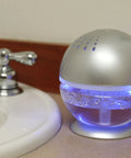 Little Squirt Glowing Water Air Revitalizer And Diffuser With 10ml Lavender Oil emitting blue light, placed on bathroom counter.