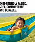 Child smiling in Ultra Lightweight Camping Hammock With 500 Lb Capacity And Tree Straps for travel, bright yellow and teal.