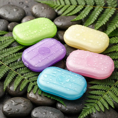 Grab and Go Disposable Soap Sheets Set, 5 colorful boxes on wet rocks with ferns, perfect for travel and outdoor adventures.