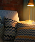 Cozy living room scene with a lamp illuminating patterned cushions on a sofa, showcasing warm lighting ambiance.