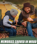 Father and son whittling wood blocks together outdoors, sitting near a yellow tent, focusing on wood carving activity.