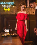 Woman in a red dress standing beside a man at a table with food and wine in a dimly lit room