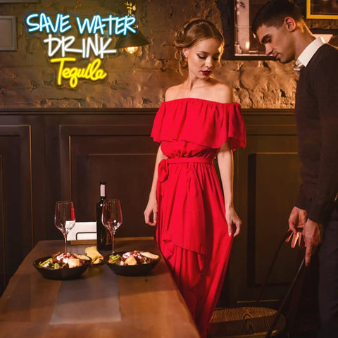 Woman in a red dress standing beside a man at a table with food and wine in a dimly lit room