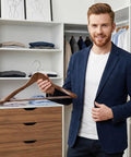 Man holding premium vintage wood hanger in closet with suits and shirts. Premium Vintage Wood Hangers 12-Pack With Wide Shoulders And Non-Slip Grips For Coats Jackets And Suits 360 Degree Rotating Closet Organizer Durable Space Saving Design For A Clean Pro Grade Wardrobe.