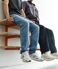 Two men sitting on a Heavy Duty Wall Mounted Lumber Rack Go Big Or Go Home Holds Over A Ton, orange steel shelf.