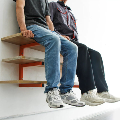 Two men sitting on a Heavy Duty Wall Mounted Lumber Rack Go Big Or Go Home Holds Over A Ton, orange steel shelf.