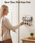 Woman using wall mounted key holder with five hooks and metal wire mesh mail basket, entryway organizer for keys and mail.