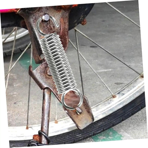 Grab This 8 Piece Small Compression Spring Kit With Hook Ends Perfect For Elevating Electric Vehicle Parking Stands And Securing Ladder Foot Supports To Keep Your Gear Rock Solid And Ready For Any Adventure. silver hook-end compression spring on rusty bike frame