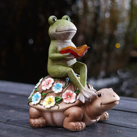 Solar Frog Riding Turtle Garden Statue For Outdoor Patio Yard Balcony Decor Totally Boss Gift For Garden Lovers With Auto Solar Power For Daylight Charging And Gentle Night Glow featuring a frog holding a book on a turtle with flower decorations