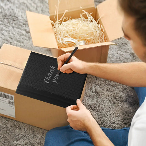 Person writes 'Thank You' on Black Bubble Mailers 6x10 Inch 100 Pack Padded Envelopes With Inner 6x9 Usable Size Opaque Waterproof Cushioning Mailers