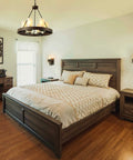 Farmhouse Wagon Wheel Six Light Chandelier With Frosted Seeded Glass Shades hanging in rustic bedroom with wood furniture.