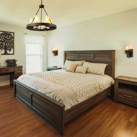 Farmhouse Wagon Wheel Six Light Chandelier With Frosted Seeded Glass Shades hanging in rustic bedroom with wood furniture.