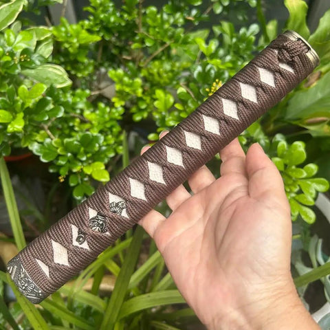 Hand holding Sword Handle Tsuka With Real Samegawa Stingray Skin And Alloy Copper Iron Fittings Dope Grip Against Green Plants