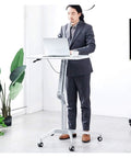 Man using Smooth Glide Height Adjustable Mobile Laptop Desk And Sit Stand Workstation Table with Easy Roll Castors in office.