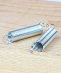 Two zinc-plated springs from Must-Have Compression Spring Wire Kit With Zinc Plated Steel Extension Springs, 200-Piece Set on wood surface