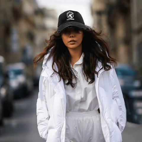 Woman wearing Trust Me I Am An Electrician Hat With Laser Engraved Design, black adjustable trucker cap with white outfit.