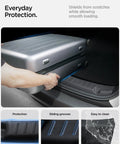 Spigen black rear bumper trunk sill guard for Tesla Model Y; installed, shown while loading luggage.