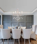 Plug In Crystal Ceramic White Chandelier With Clear Cord And Toggle Switch over a dining table with beige chairs in modern setting.