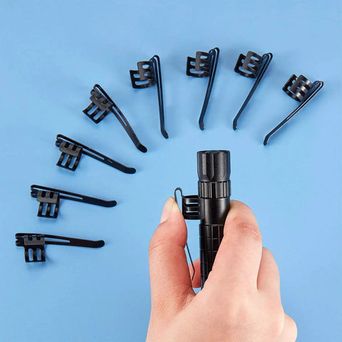 Hand holding penlight with 20 Pack Metal Flashlight Clips For Removable Accessories arranged in a circle on blue surface