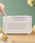 Great Slick And Totally Nifty Mini Countertop Ice Maker With 12V Car Adapter And Fast Freeze Cycle Portable Cube Maker For Rv Campers Cars Homes And Road Trips Everywhere on a table with hand pressing button.