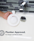 Overflow Drain Cover For Deeper Warmer Baths With No Fuss Suction Cups Universal Fit Spa Accessory Easy Install Adds Inches Of Water For A Deeper Cozy Soak Spa Vibe Works With Most Tubs being held by a hand near a bathtub overflow outlet.