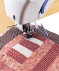 Honbay quilting guide bar for Brother/Singer/Janome, attached to a sewing machine, guiding pink patchwork quilt.