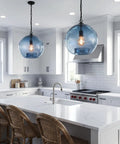 CASAMOTION Modern Farmhouse Blue Glass Globe Pendant Light 11" Dia. hung in kitchen with white cabinets and marble countertop.