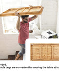 Man carrying Big Floor Desk Tray With Folding Legs, Adjustable Low Coffee Table, bamboo top, shows portability and storage ease.