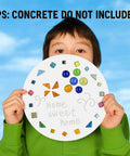 Child holding a decorated stepping stone from the DIY Stepping Stone Kit With 20 Round Molds 250g Mosaic Tiles And 3 Carving Tools.