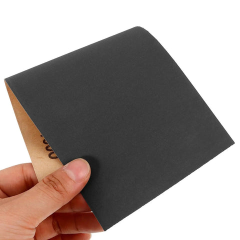 Hand holding a sheet from Wet And Dry Sandpaper Sheets Kit With Silicon Carbide Grit For Metal Wood Furniture Cars And Electronics
