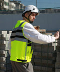 High Visibility Reflective Safety Vest With Heavy Duty Construction And Plenty Of Pocket Space For Tools On Any Job Site Hella Bright Orange Unisex Work Vest In Three X Large Size, worn by worker on site.