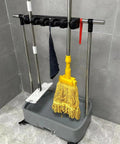 Heavy Duty Mop And Broom Holder Organizer Caddy For Garage And Workshop Storage Rack Keeps Cleaning Tools Handy And Off The Floor, Ideal For Laundry Rooms, Kitchens, Hotels And Property Managers, showing mops and brooms stored upright.