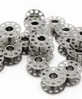 Metal sewing machine bobbins, front view, silver with perforated flanges
