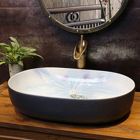Heavy Duty Premium Top Shelf Oval Ceramic Vessel Bathroom Sink For Countertop Installation With Slick Non Porous Glaze And Smooth Drainage For Restrooms displayed on wooden countertop with water reflection.